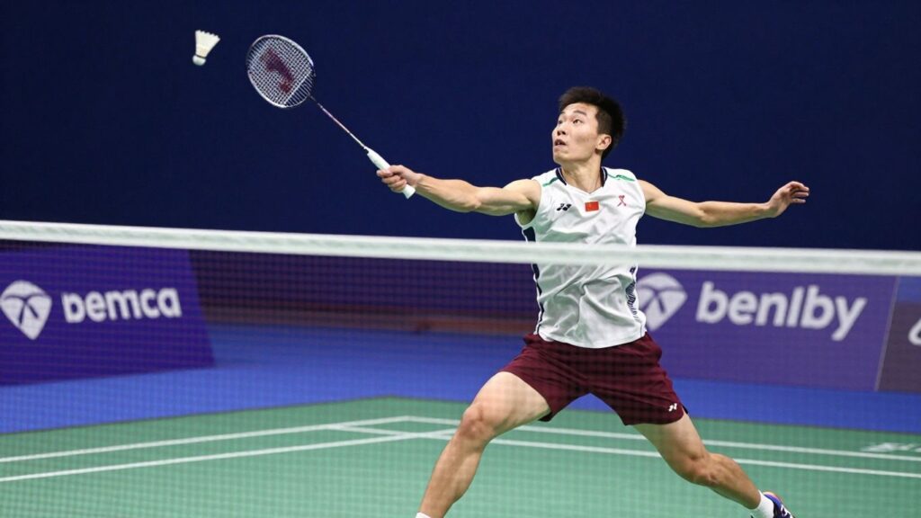 Badminton player smashing shuttlecock over the net.