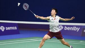Badminton player smashing shuttlecock over the net.