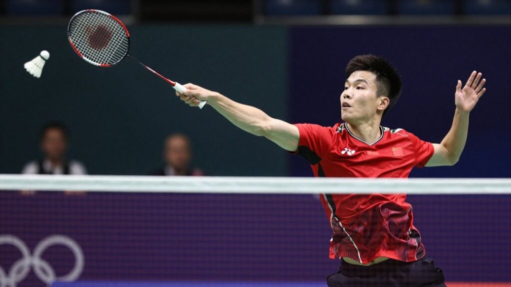 Badminton player executing a powerful serve with intense focus.