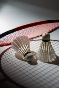 Two shuttlecocks rest on a racket.
