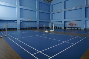 Empty indoor badminton courts with blue flooring.
