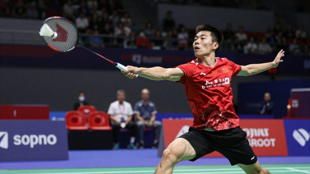 Badminton player smashing shuttlecock during a live match.