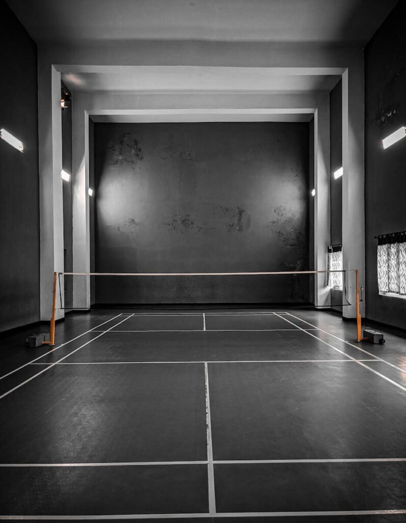 Monochrome view of an empty indoor sports court with a net and lines, ideal for badminton or squash.